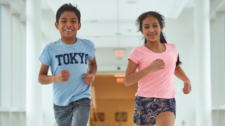 Young boy and girl running down hall