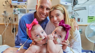 Conjoined twins Addy and Lily with their parents in a hospital room