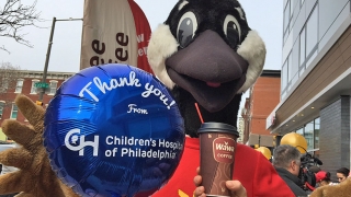 Wawa mascot holding CHOP balloon and coffee