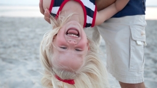 girl on beach hanging upside down smiling