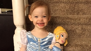 Gracia smiling sitting on steps holding her doll