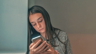 Sad teen girl holding cell phone