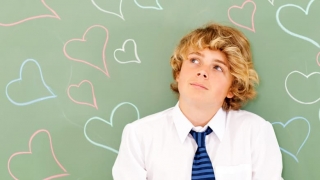 Boy standing in front of hearts drawn on chalkboard