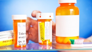 Hand reaching into medicine cabinet with pill bottles