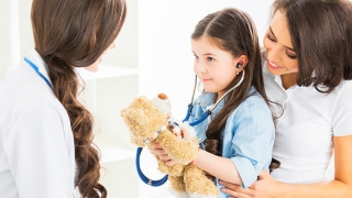 Young girl holding teddy bear and stethoscope
