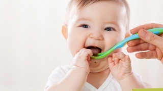 Infant being fed with plastic spoon