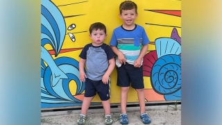 Holden and Elliott posing in front of a yellow wall