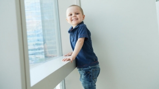 Young boy cancer patient in hospital window smiling