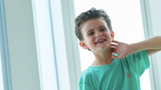 Young boy cancer patient sitting by window smiling