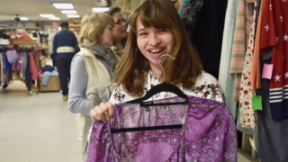 Cerebral palsy patient in thrift store holding purple shirt