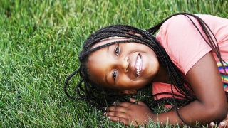 Oncology patient smiling and laying in the grass