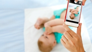 Parent taking photo of infant with phone