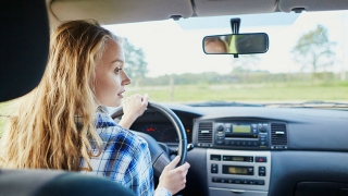 Female teenager behind the steering wheel of a car