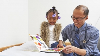 Doctor reading a book to his young patient