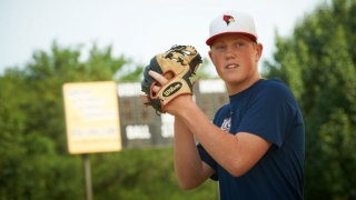 Teenage boy in baseball field holding ball and glove