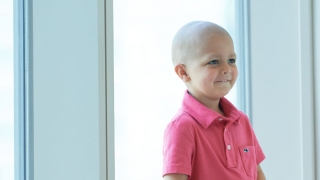 Young boy cancer patient sitting in hospital window smiling