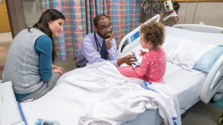 Doctor talking to child in hospital bed