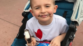 little boy GI patient in stroller eating ice cream bar
