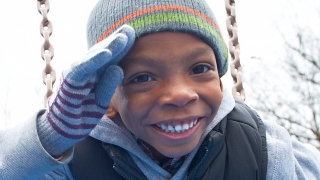 Child in winter hat on swing