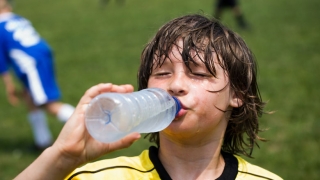 Young boy drinking water after playing soccer