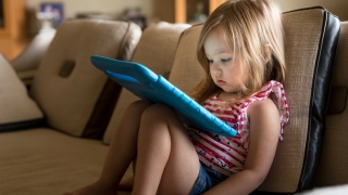 Young girl with ipad sitting on the couch