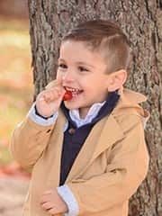 Omar smiling eating a lollipop