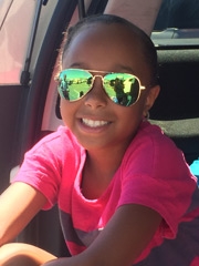 Simone sitting in car in sunglasses smiling