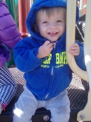 Tristan sitting at a playground smiling