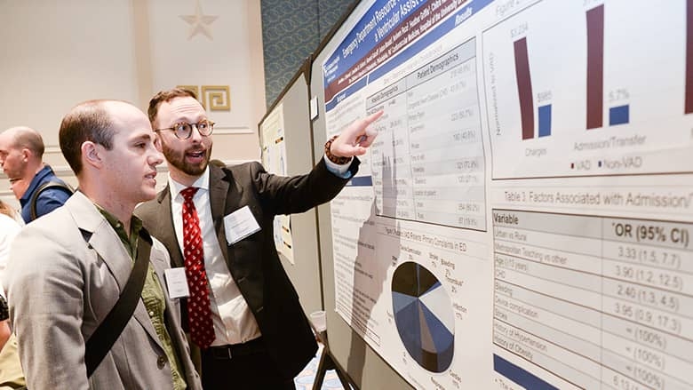 Cardiology 2020 presenter pointing to research poster