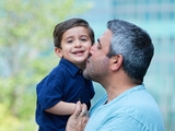 Dad kissing his smiling son in the hospital garden