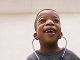 Smiling child with a stethoscope on the ears.