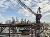 Construction of a high rise building with city skyline in the background.