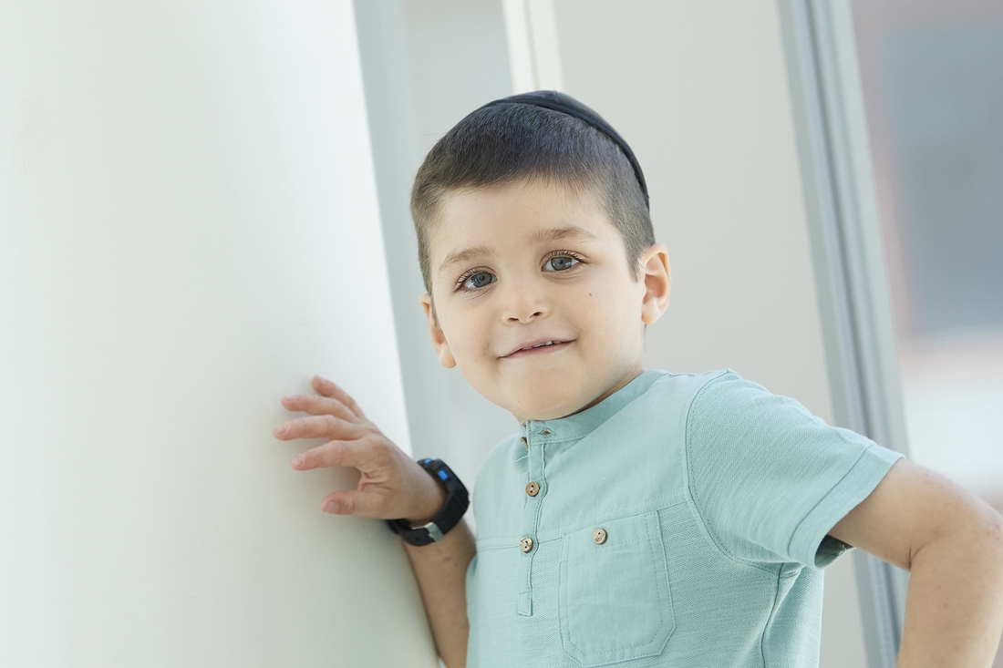 Smiling Jewish boy with green eyes and wearing a blue shirt