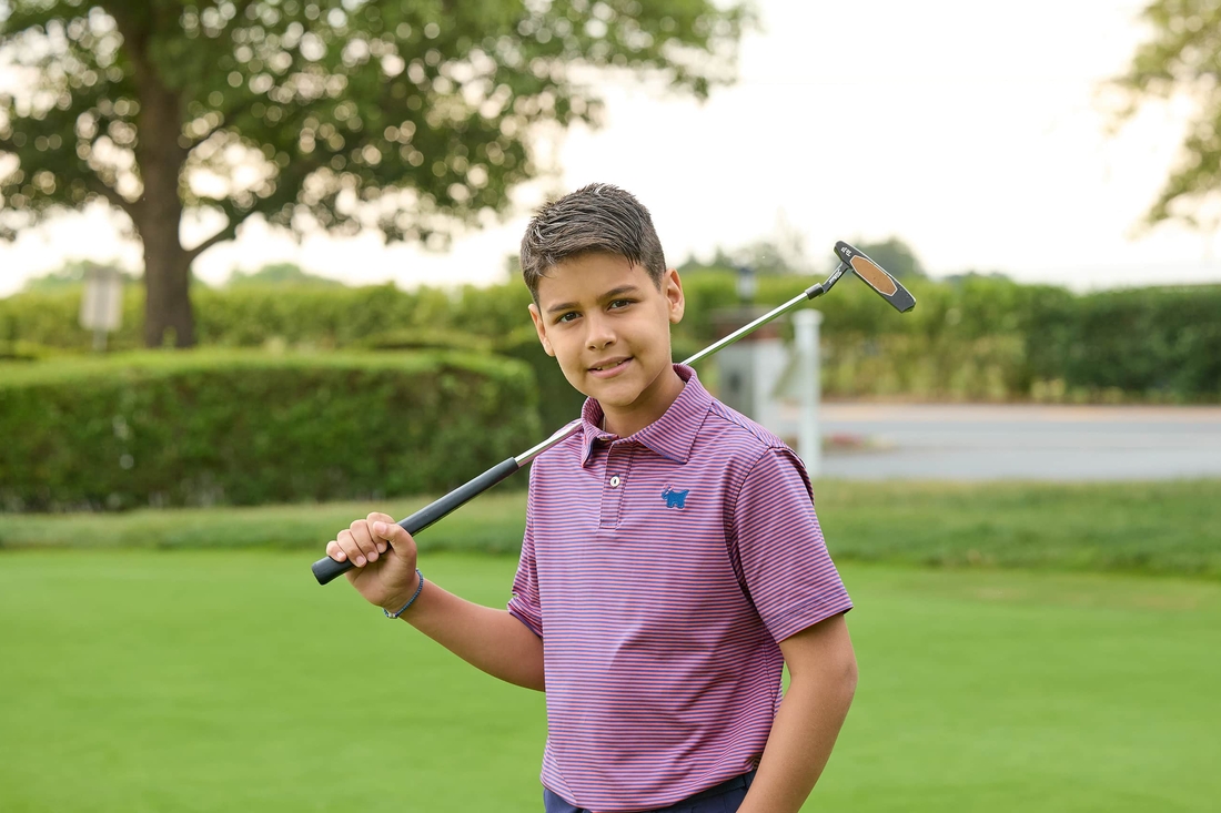 Teen boy wlking with golf club over his shouolder