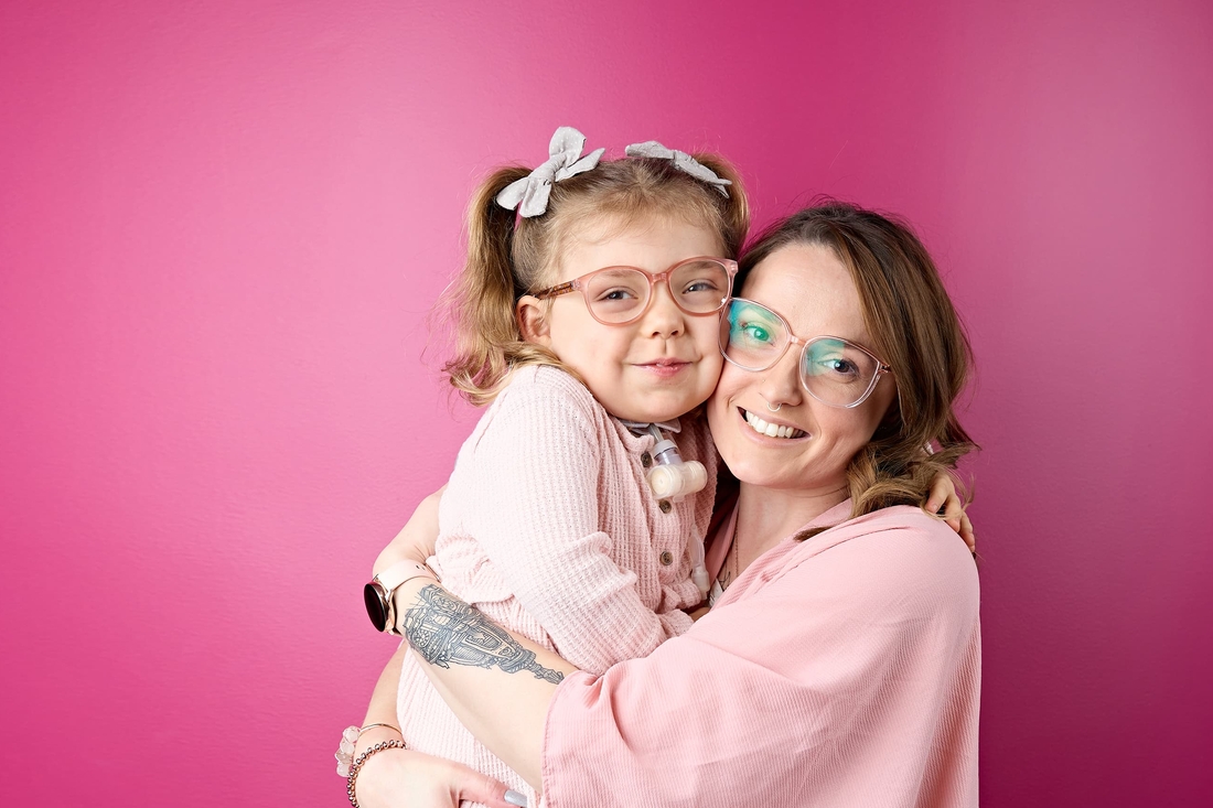 Mom hugging her blonde daughter with a tracheostomy