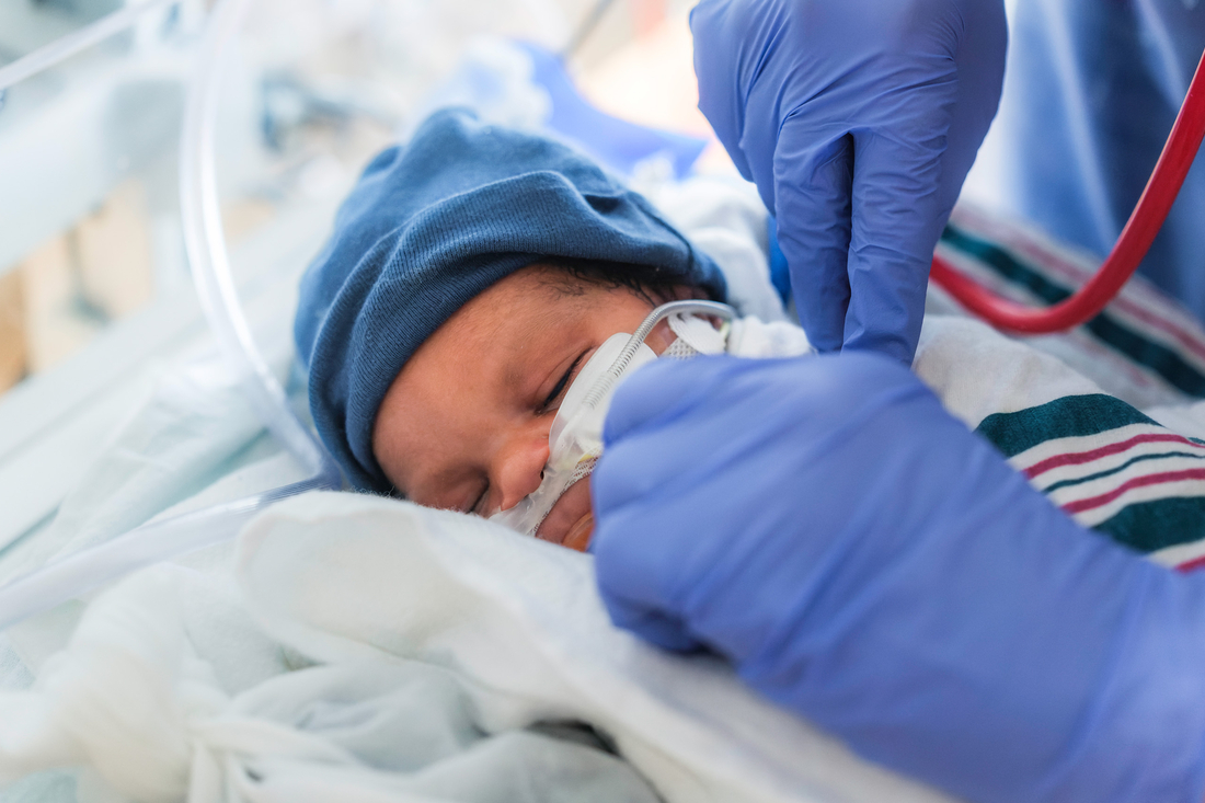 Delicate baby with nasal cannula and caring hands