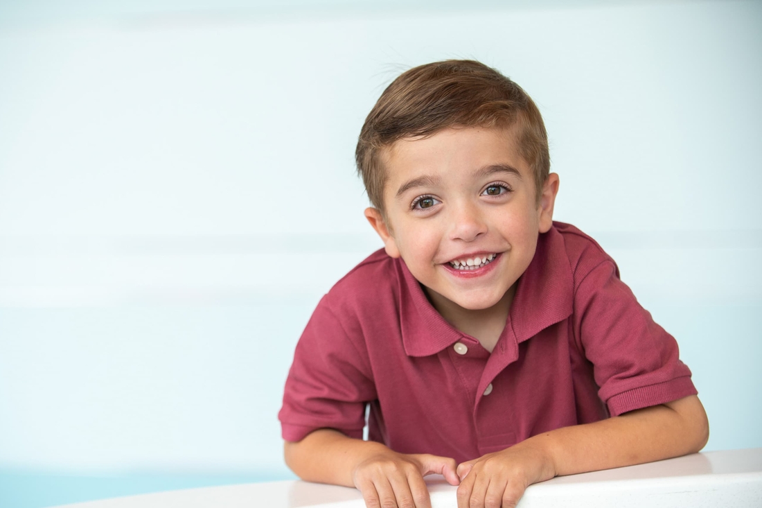 Smiling kid with green eyes and red polo shirt.