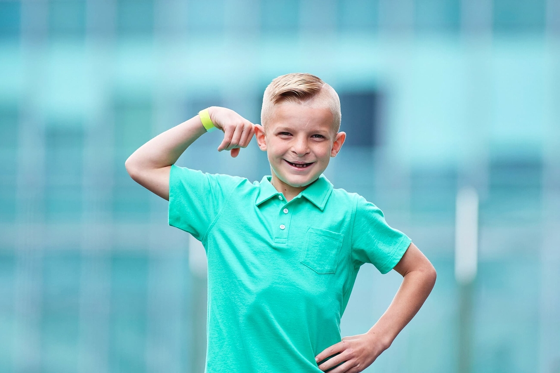 Smiling blonde boy craniofacial anomality in front of building.
