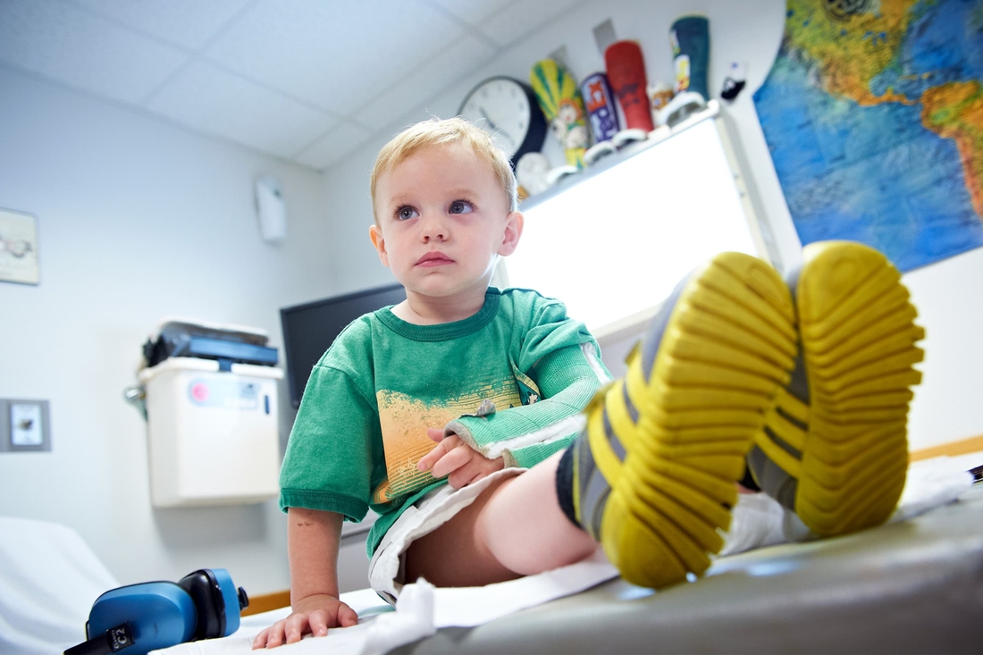 Young boy with broken arm sitting on patient table.