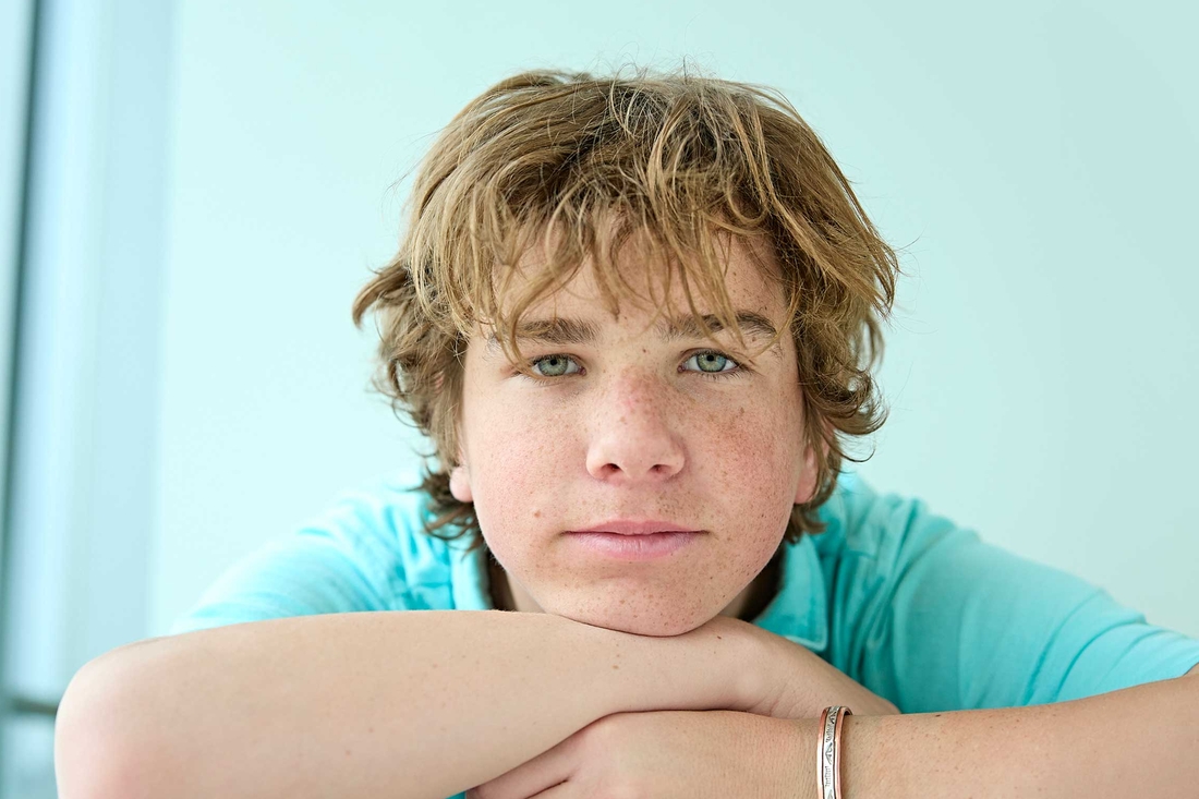 Boy in teal shirt leaning on his hands
