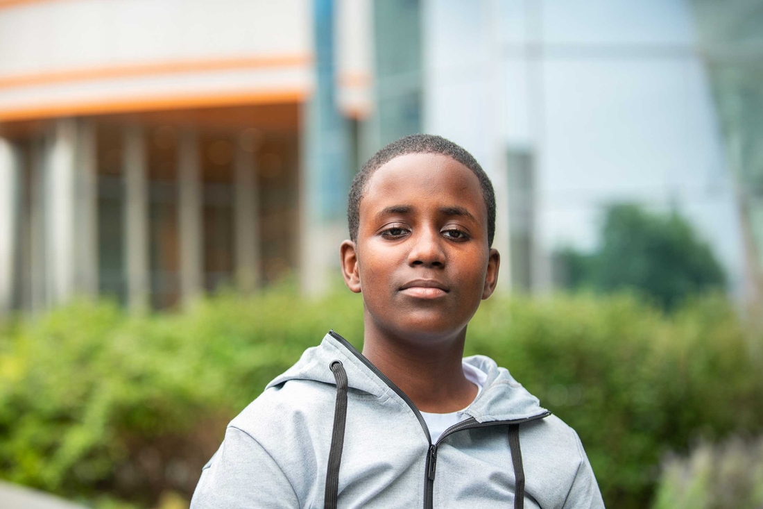 Boy with grey sweatshirt standing outside