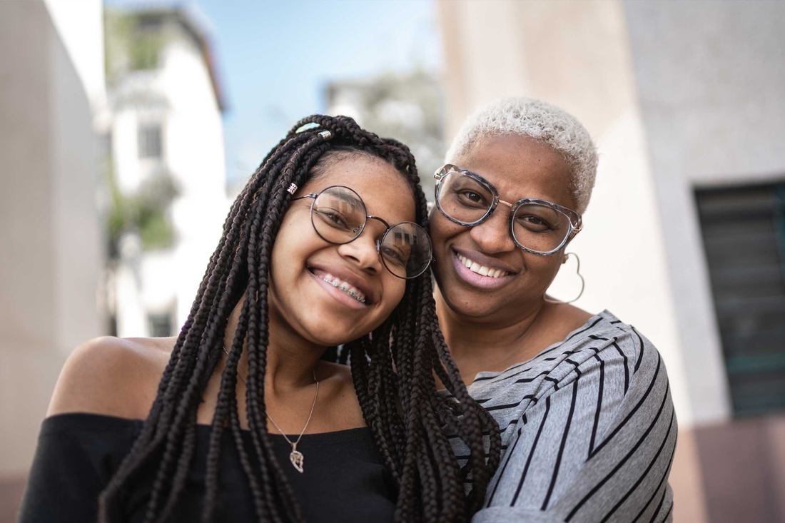 Smiling and hugging mother and daughter wearing glasses