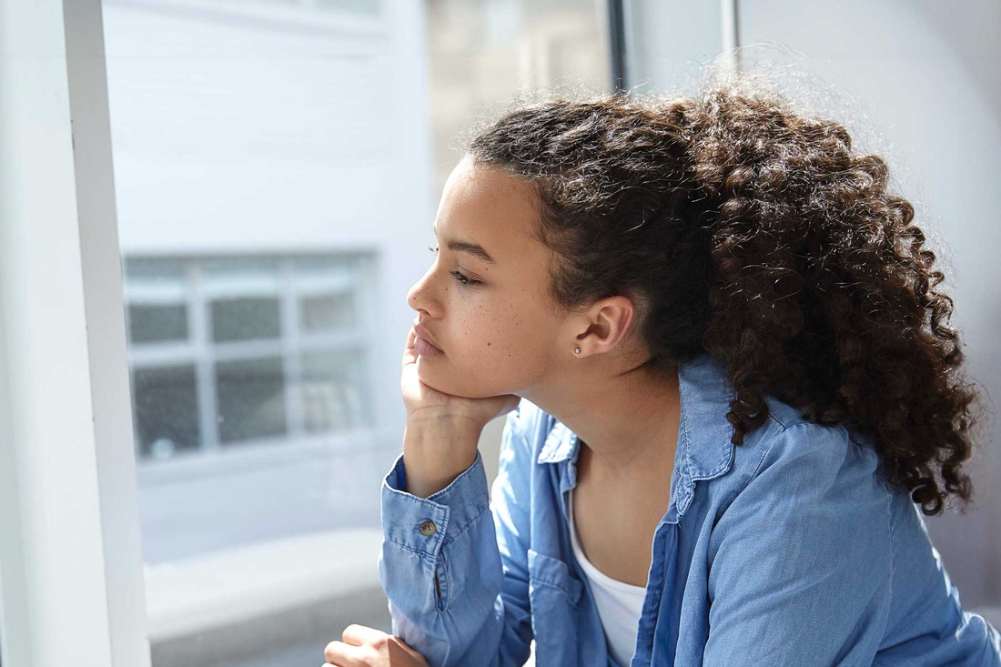 Young teen looking out window