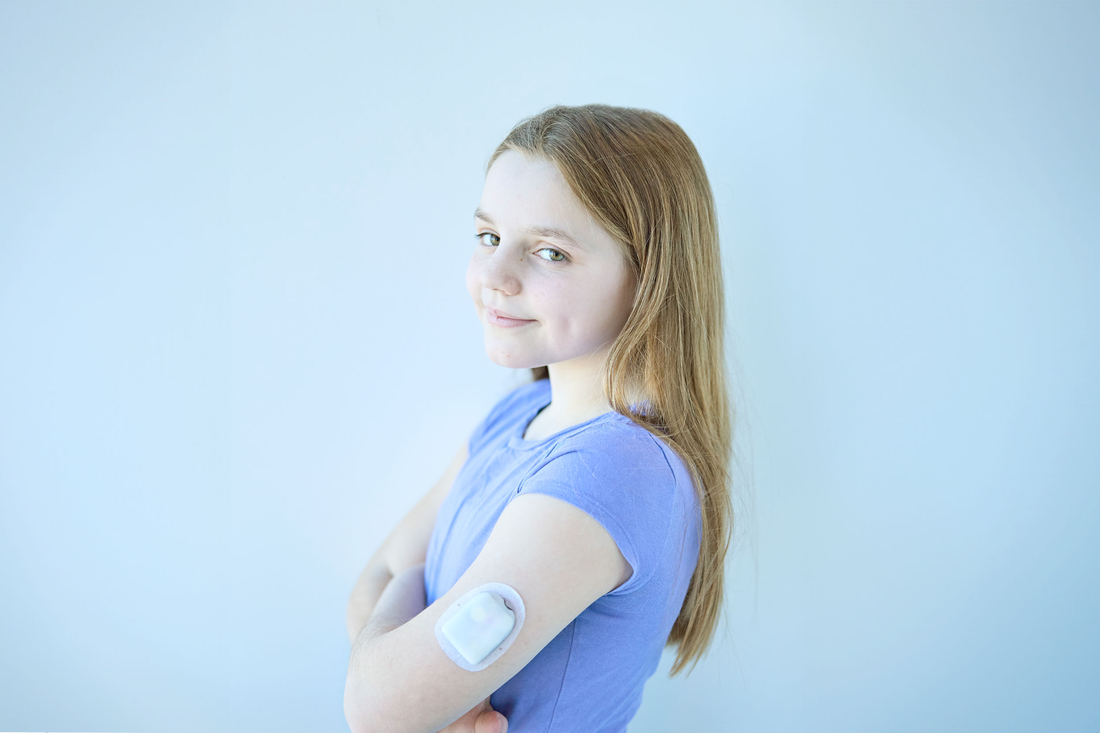 Smiling girl in blue shirt with a flash monitor on her arm