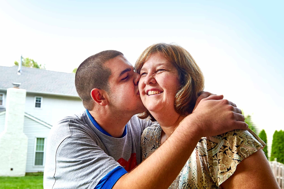 Son hugging his mom and placing a kiss on her cheek