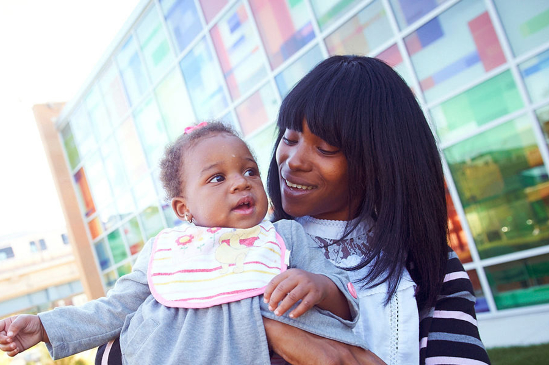 Mom holding her infant and smiling at her.