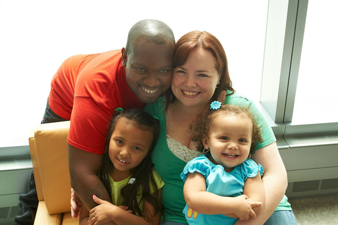 Mother, father, and two daughters smile for the camera.