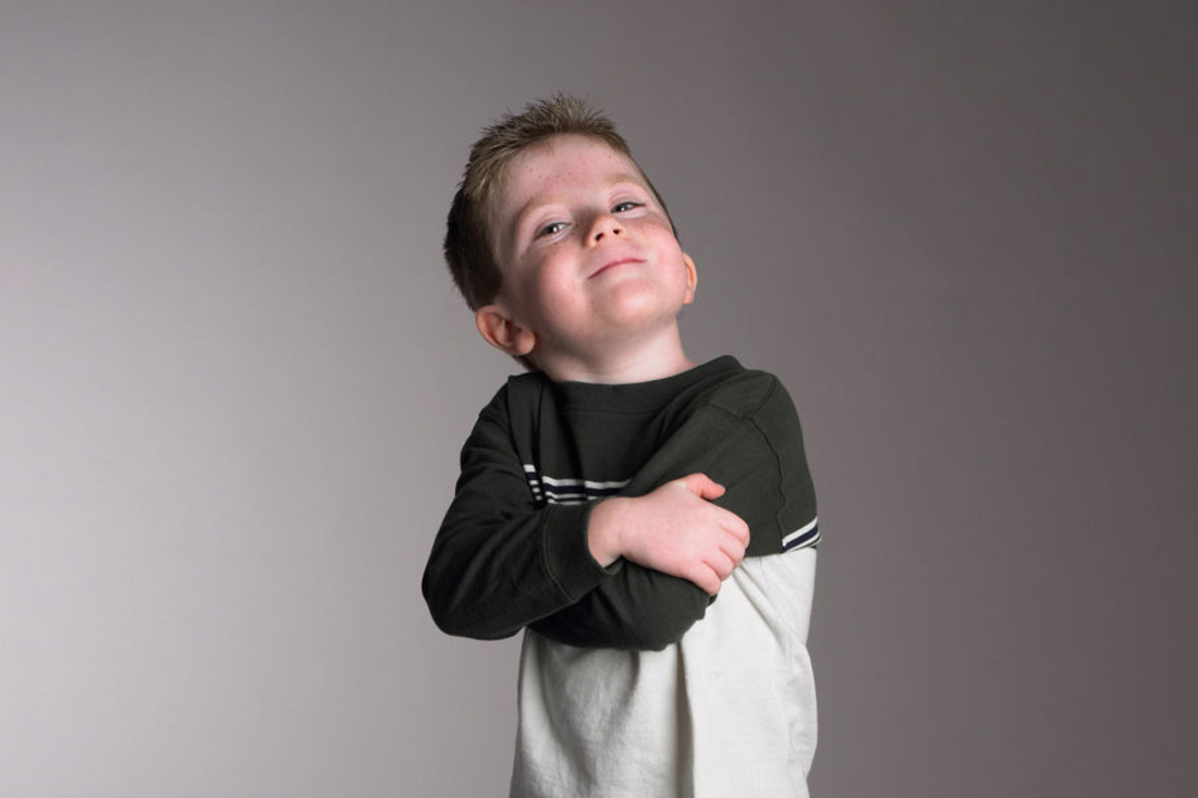 Young boy crossing his arm and smiling at the camera.