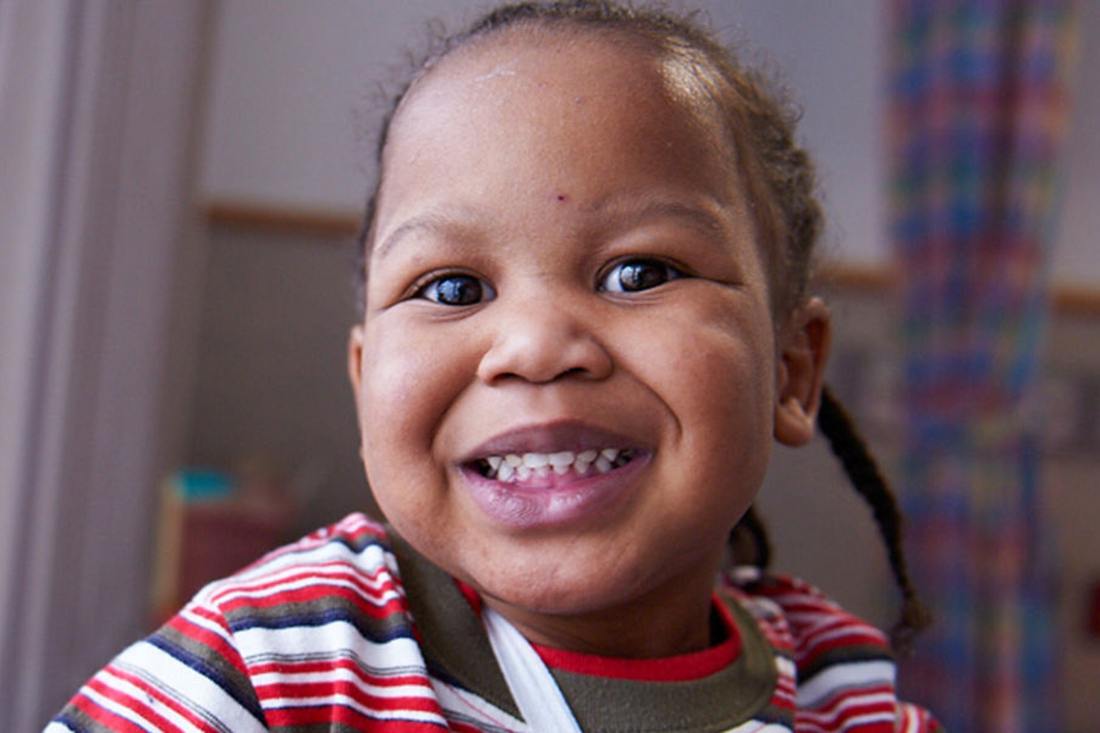 Closeup of a young child smiling in hospital room