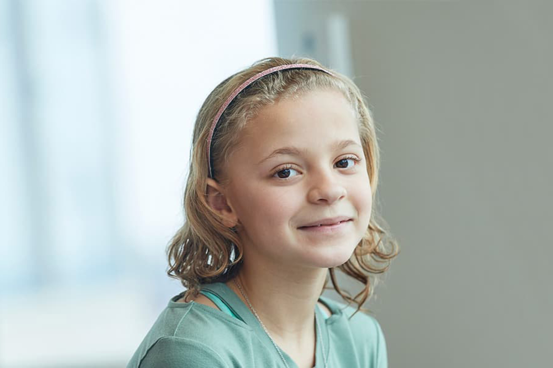 Young blonde girl smiles at the camera.